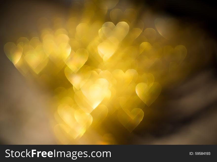 Festive background with defocused golden glitters, bokeh in a shape of a heart. Festive background with defocused golden glitters, bokeh in a shape of a heart.