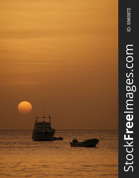 Two boats in front of a setting sun at dusk. Two boats in front of a setting sun at dusk