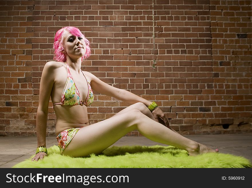 Pretty Woman in a Bikini with Pink Hair on Green Rug. Pretty Woman in a Bikini with Pink Hair on Green Rug