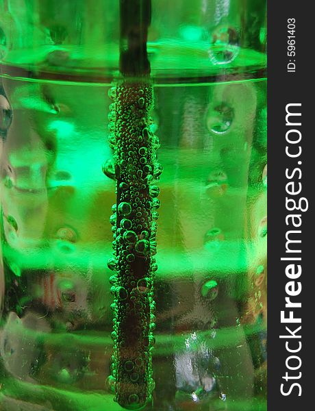 A close detail of a straw in a green bottle covered in bubbles. A close detail of a straw in a green bottle covered in bubbles