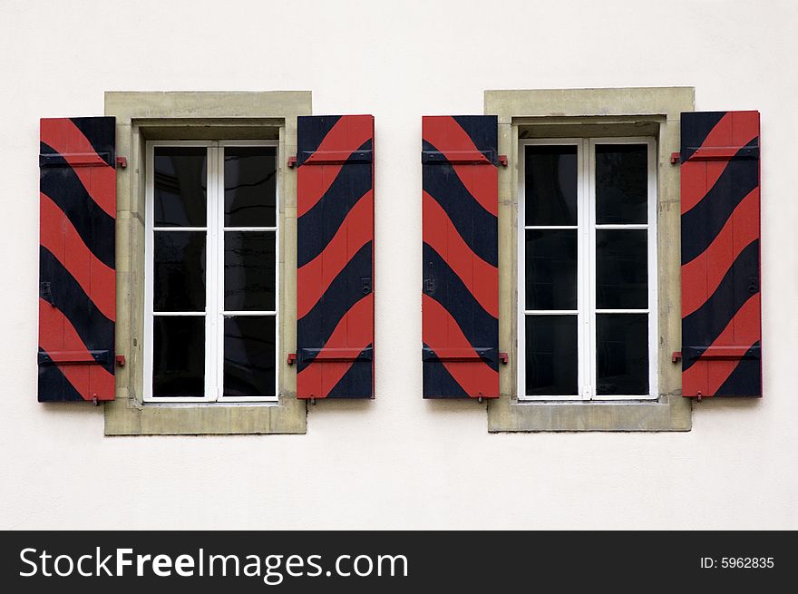 Two windows with blinds painted wavy in red and black. Two windows with blinds painted wavy in red and black