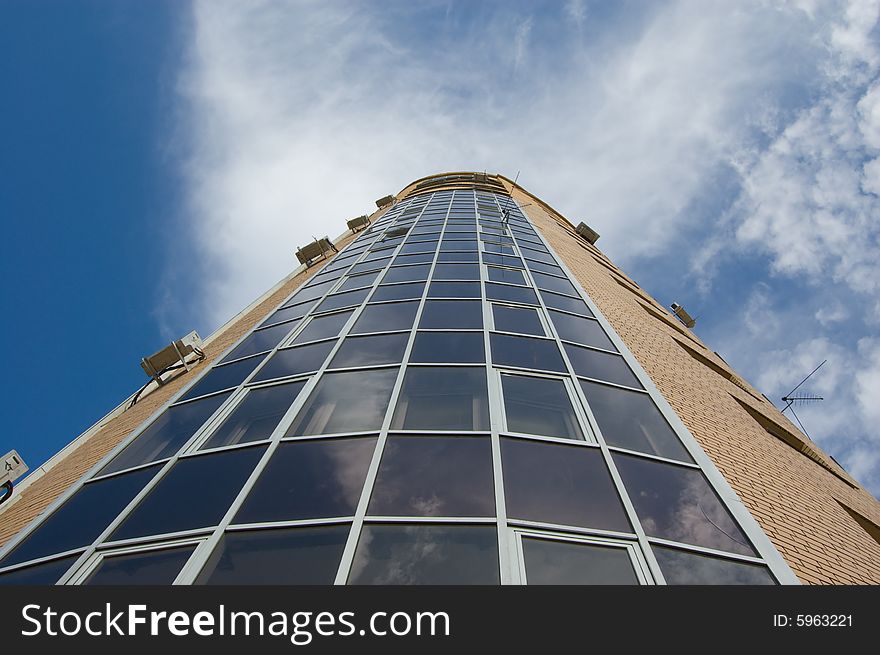 Multistory house of glass and red and yellow bricks in blue sky. Multistory house of glass and red and yellow bricks in blue sky