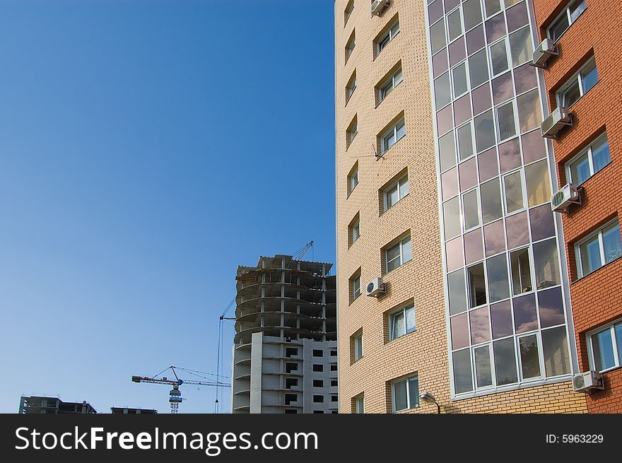 New brick multistory house in the foreground, construction works and tower crane in the background. New brick multistory house in the foreground, construction works and tower crane in the background