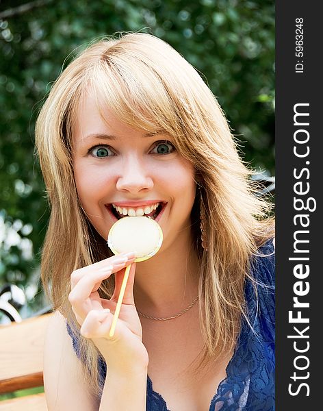 Pretty playful girl sits on the bench and eats a candy. Pretty playful girl sits on the bench and eats a candy