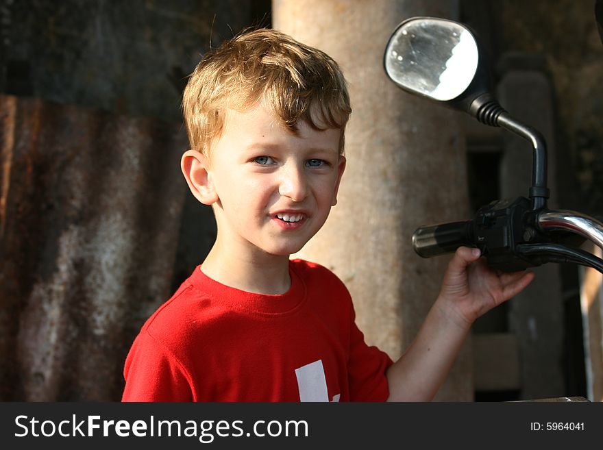 Young boy holding onto the handle of a motorbike. Young boy holding onto the handle of a motorbike