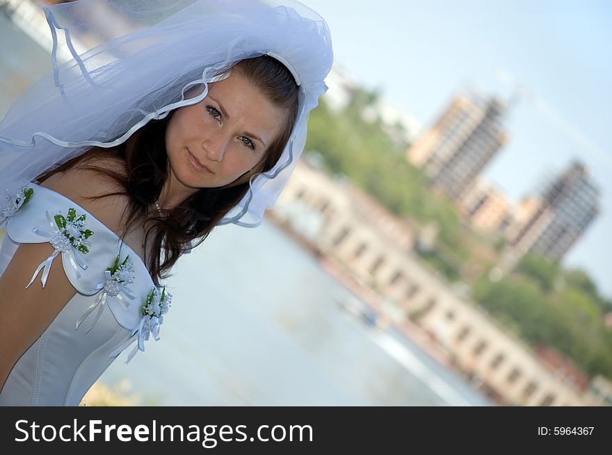 The bride against the river and a city, looks in the cam. The bride against the river and a city, looks in the cam