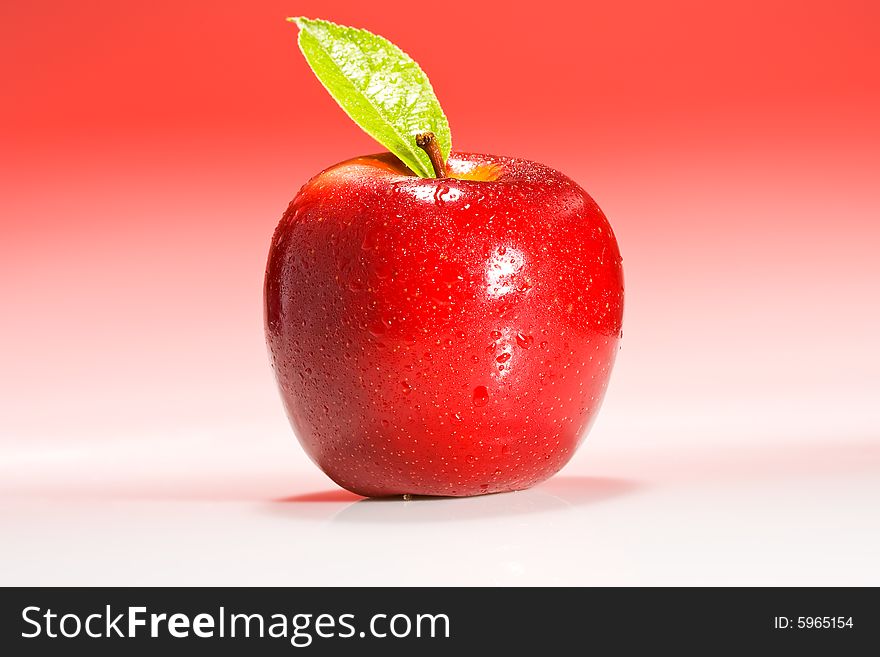 Red Shinny Apple with water drops and a green leaf on a red gradient background. Red Shinny Apple with water drops and a green leaf on a red gradient background