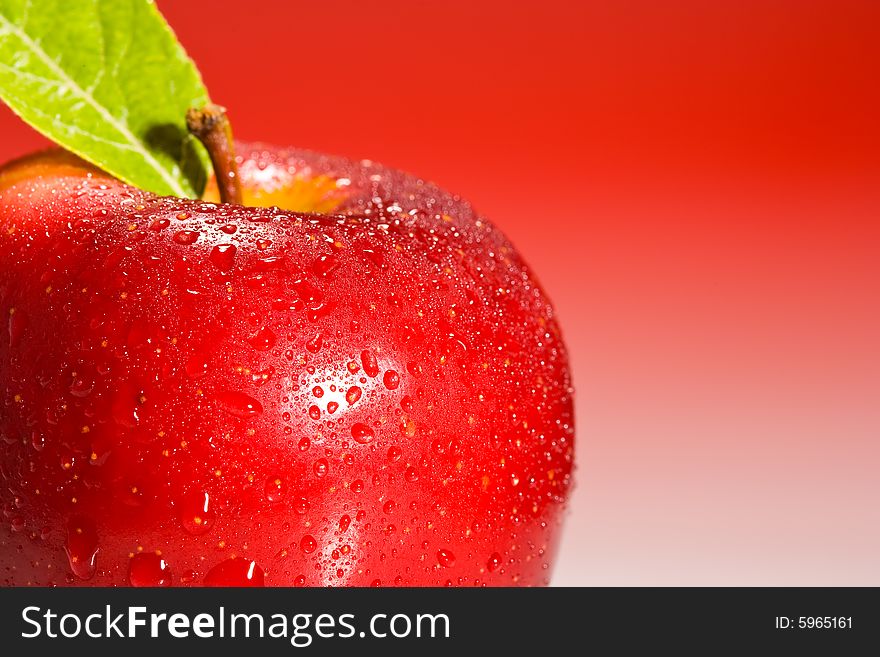 Red Shinny Apple with water drops and a green leaf on a red gradient background. Red Shinny Apple with water drops and a green leaf on a red gradient background