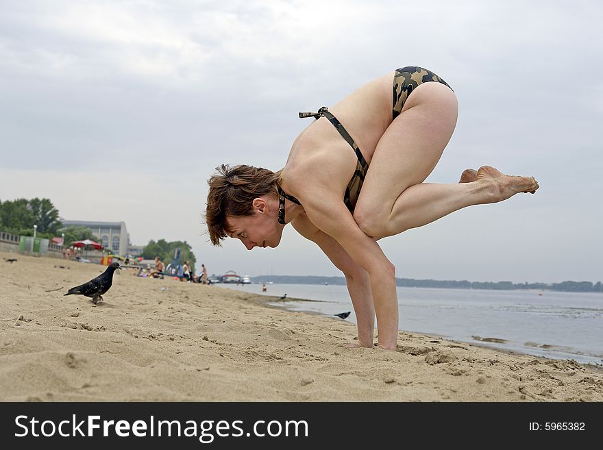 The yoga is occupied with exercises on the beach. The yoga is occupied with exercises on the beach