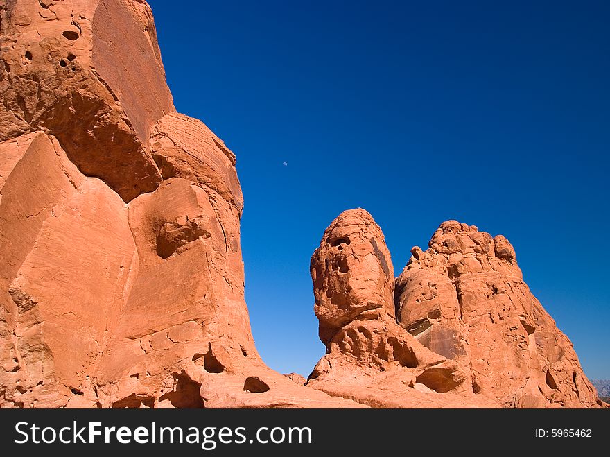 Red rock with moon under blue sky