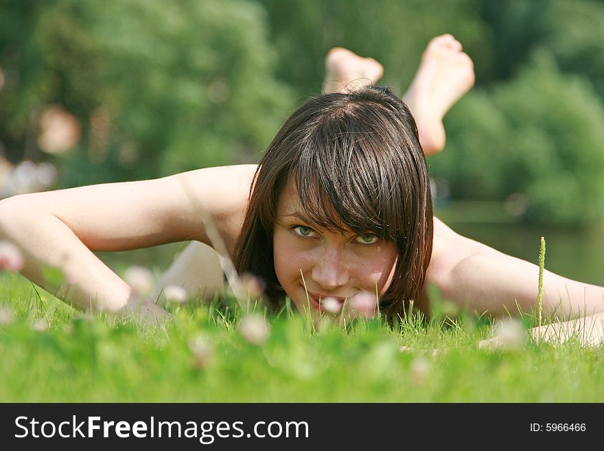 The beautiful girl lays on a green grass. The beautiful girl lays on a green grass