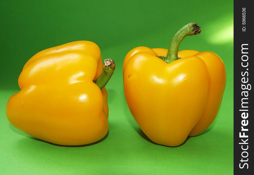 Two yellow pepper isolated on green