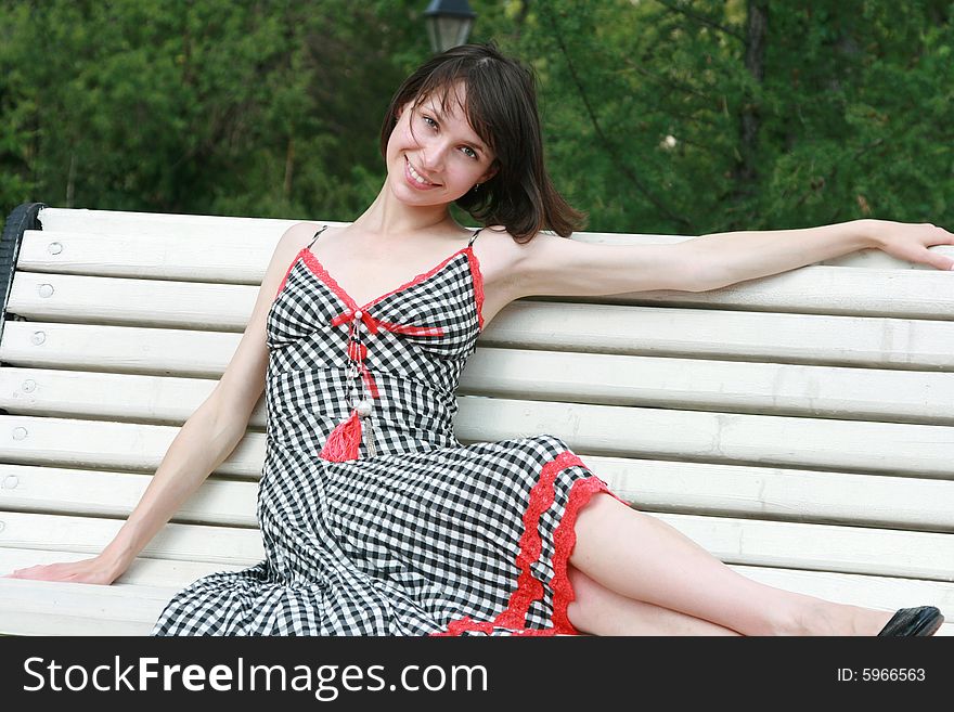 The beautiful girl poses on a bench. The beautiful girl poses on a bench