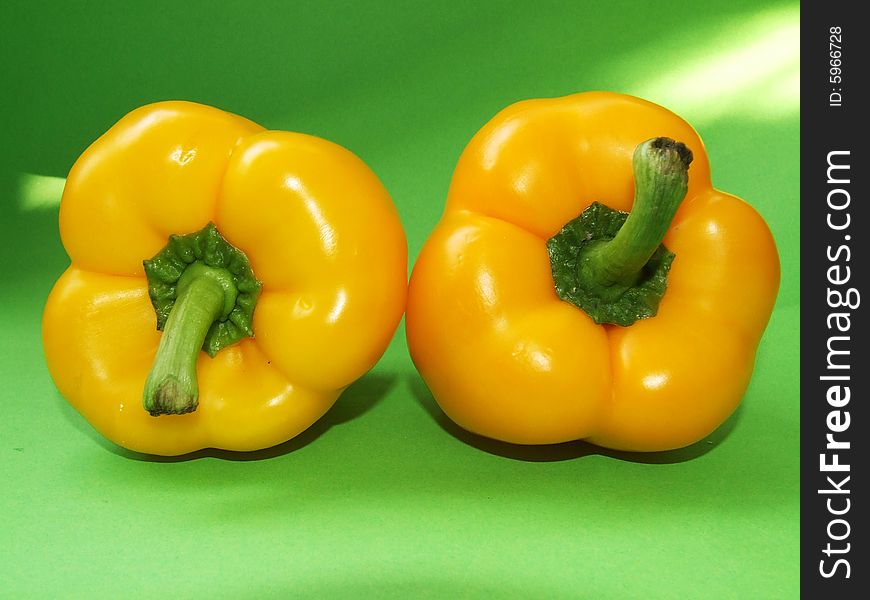 Two yellow pepper isolated on green