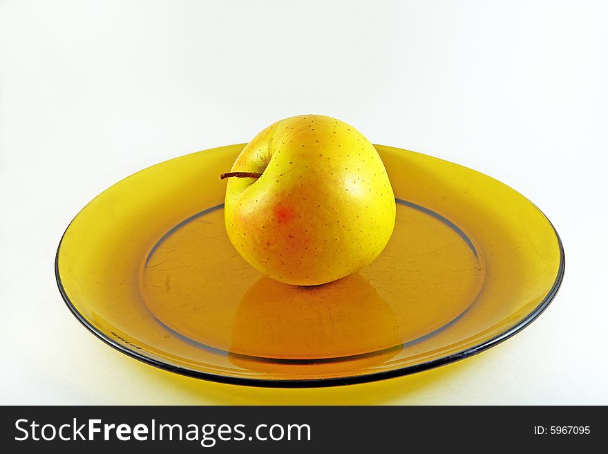 The yellow apple on the yellow dish