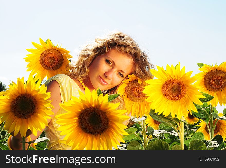 Portrait of the girl in an environment of flowers of a sunflower