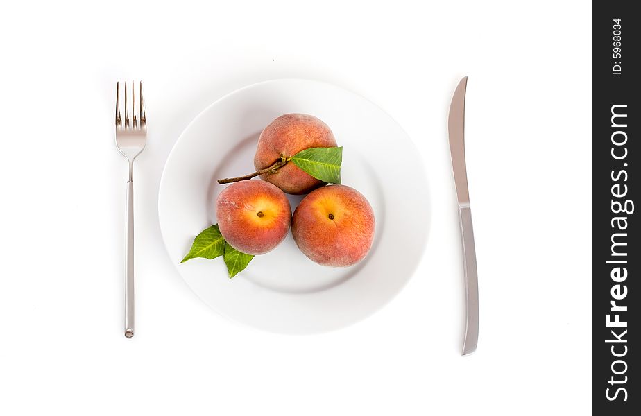 Peaches on a plate with fork and knife on the side