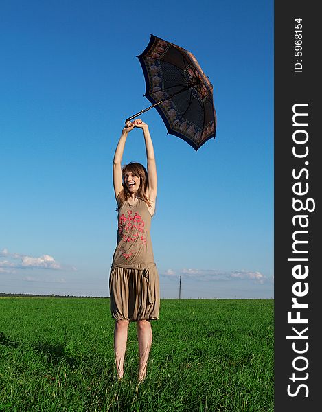 Happy girl with umbrella in a field