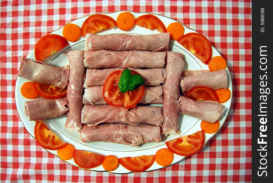 A dish with ham, tomatoes, carrots and two leaves of basil. A dish with ham, tomatoes, carrots and two leaves of basil