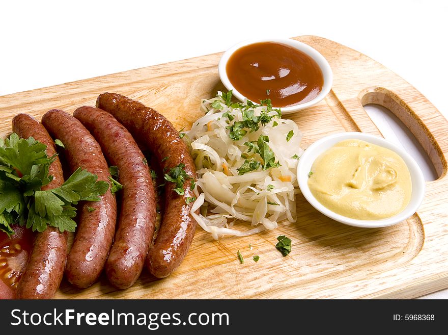 Four long frankfurters with sauerkraut, herbs and two kinds of sauces - mustard and ketchup on wooden board