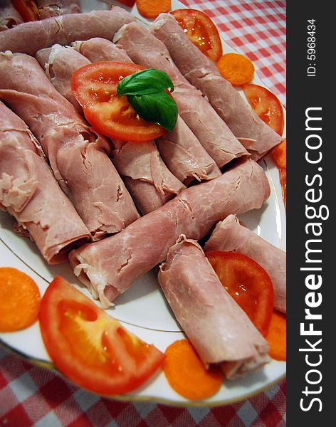 A dish with ham, tomatoes, carrots and two leaves of basil. A dish with ham, tomatoes, carrots and two leaves of basil