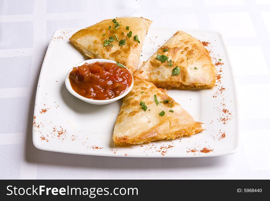 Three pieses of cheese flat with tomato-pepper sauce on white plate