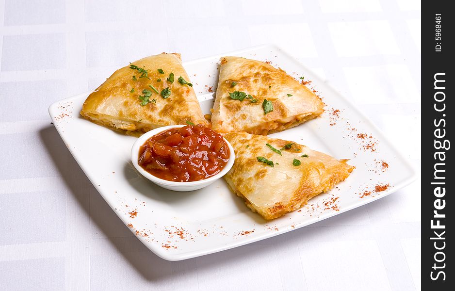 Three pieses of cheese flat with tomato-pepper sauce on white plate