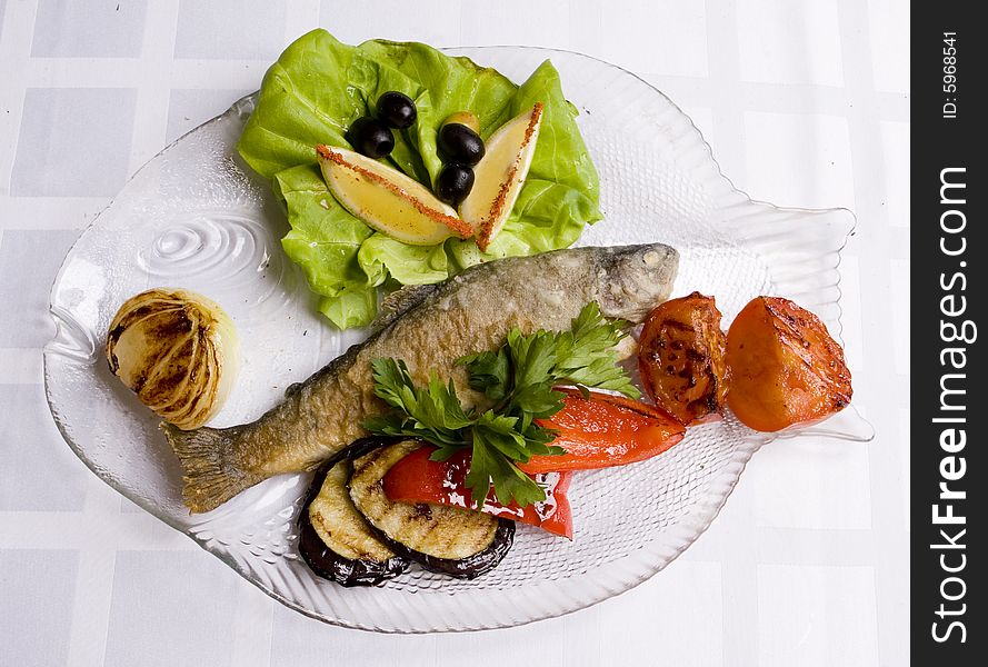 Fried fish with vegetables, salad and lemon