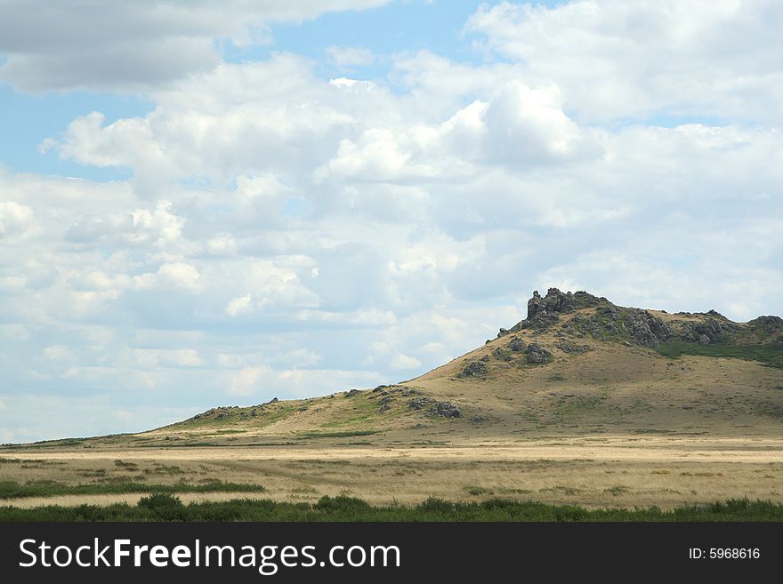 Steppe landscape. hill covered dry grass. sky with clouds