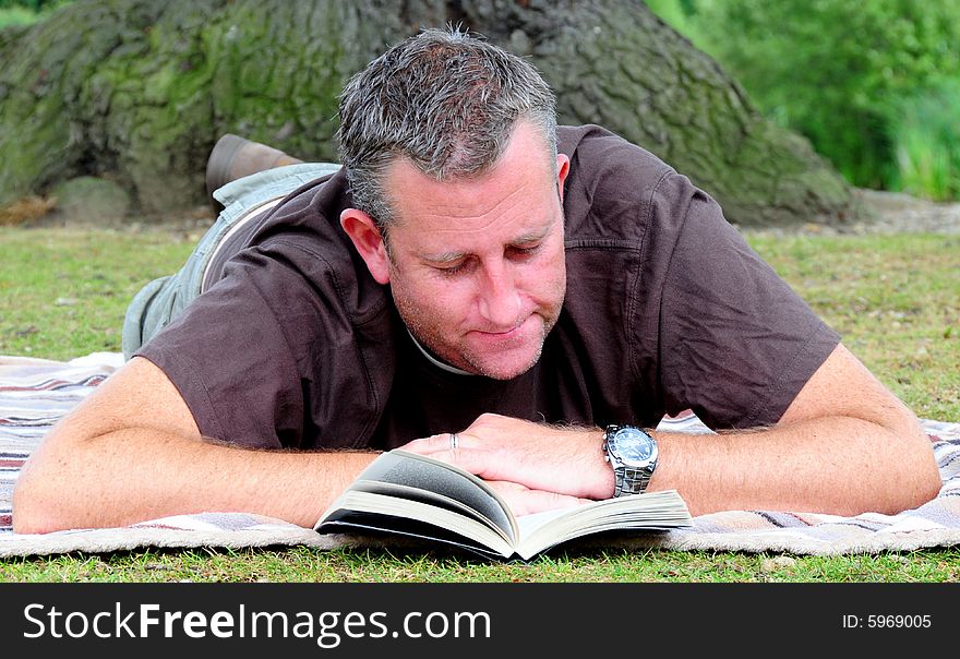 Shot of a man reading his book in the park