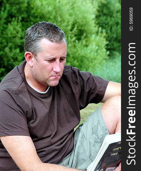 Shot of a man reading his book in the park