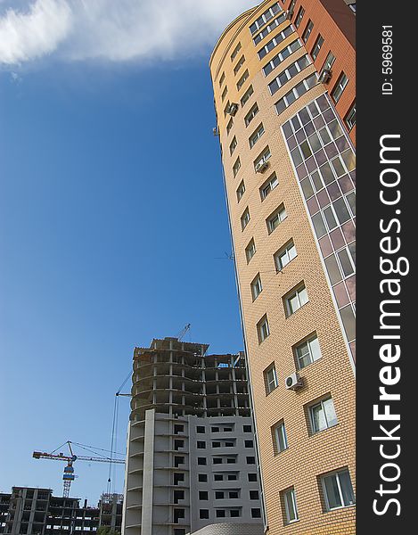 New brick multistory house in the foreground, construction works and tower crane in the background. New brick multistory house in the foreground, construction works and tower crane in the background