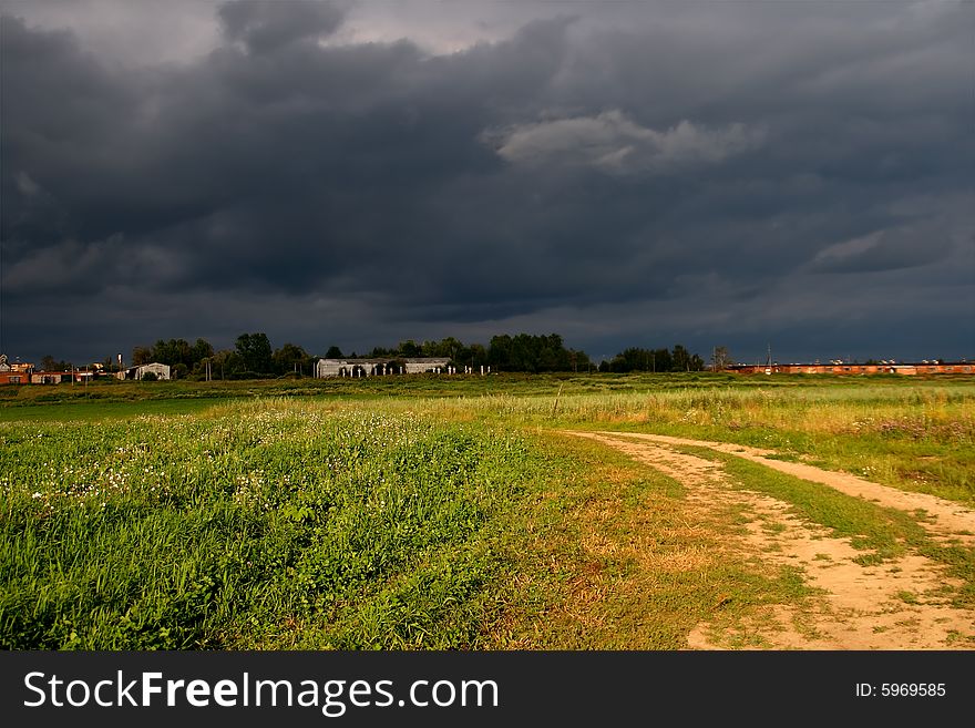 In an open country the sun still shines, but thunderclouds are in the distance visible. In an open country the sun still shines, but thunderclouds are in the distance visible