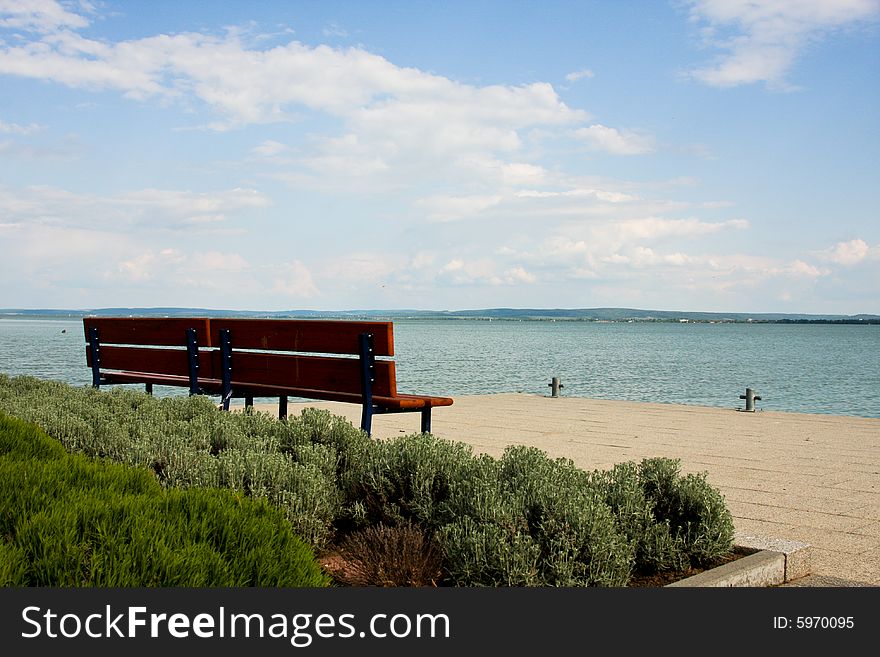 A lonely brown bench in summer by Lake Balaton, Hungary, Central Europe. A lonely brown bench in summer by Lake Balaton, Hungary, Central Europe
