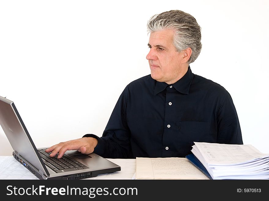 A businessman at work in his office writing a report with a laptop