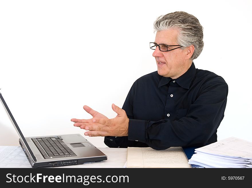 A businessman at work in his office writing a report with a laptop