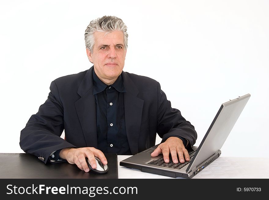 A businessman at work in his office writing a report with a laptop