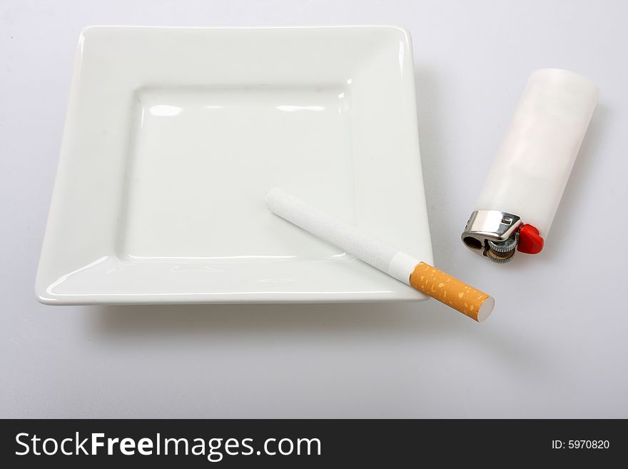 Unlit cigarette on white ashtray isolated on white white lighter to the side
