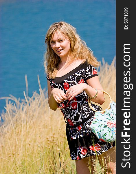 Young beautiful girl with bag over blue river background