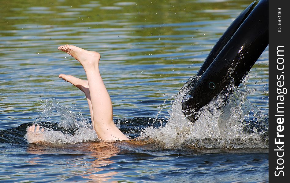 The boy is diving backwards jumping from the tube in a small lake. The boy is diving backwards jumping from the tube in a small lake.