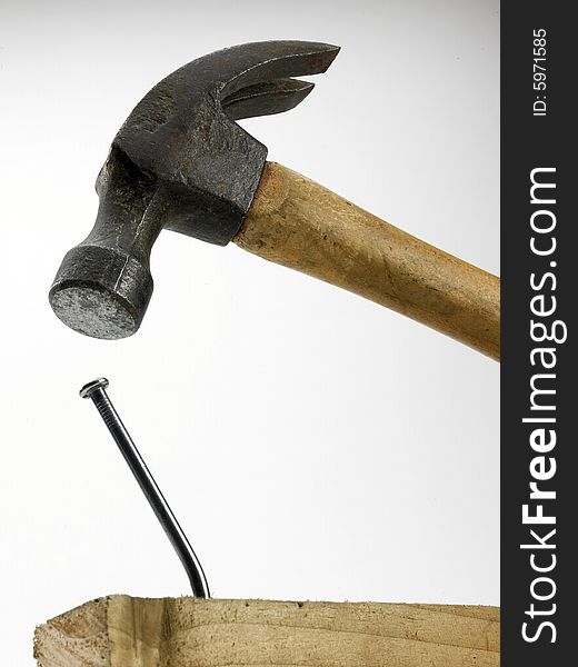 A hammer in close proximity to bent nail in piece of timber. A hammer in close proximity to bent nail in piece of timber