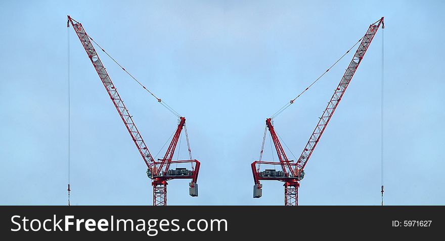 Construction cranes against sky background