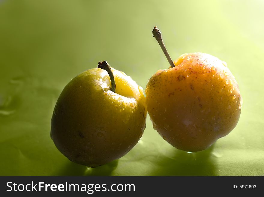 Two plums over green background