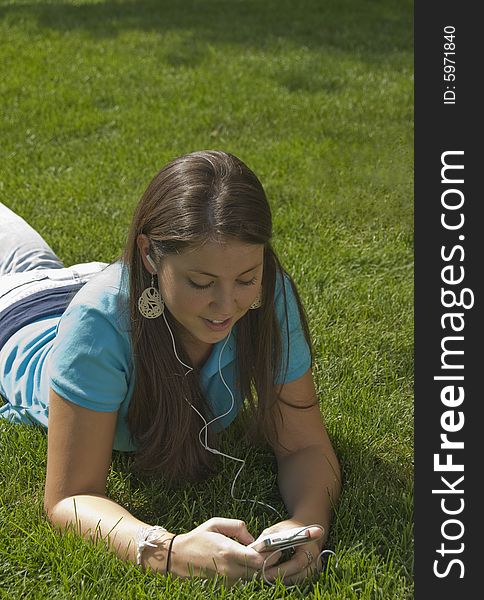 Girl relaxing in grass listening to music. Girl relaxing in grass listening to music