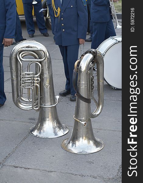 Two tubas and musicians from a military orchestra behind. Two tubas and musicians from a military orchestra behind