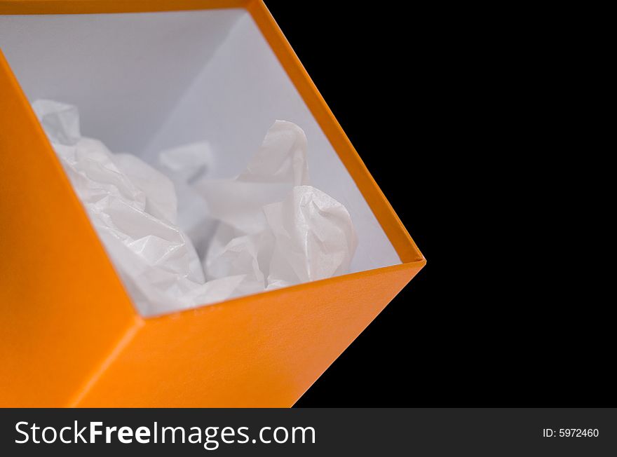 Close up of orange opened box with white paper on black background