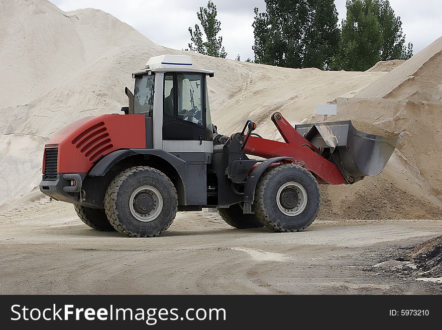 Red bulldozer at work full of sand