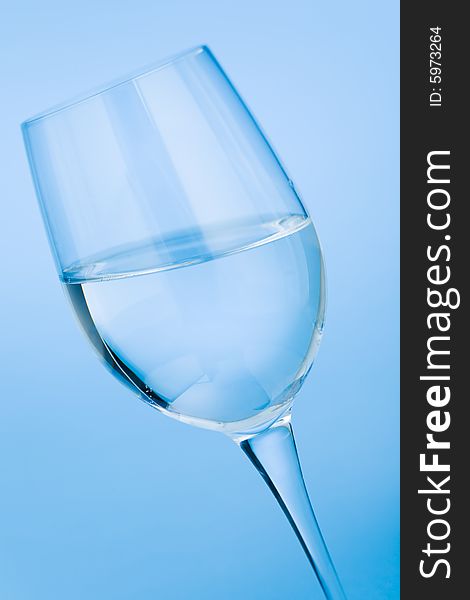 Wine glass filled with water over blue background. Wine glass filled with water over blue background