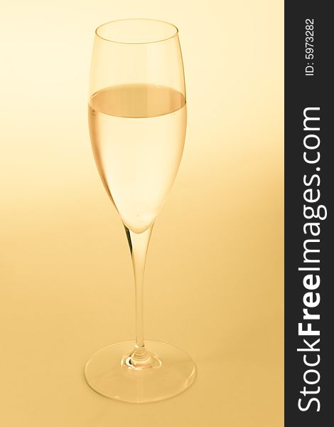 Golden sparkling wine glass over a yellow background. Golden sparkling wine glass over a yellow background