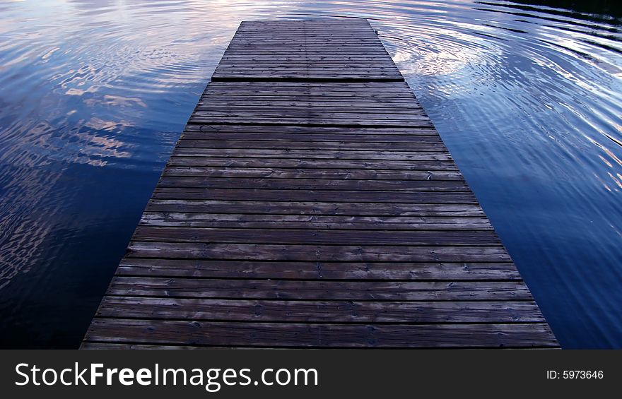 A wooden dock over the blue water. . A wooden dock over the blue water.